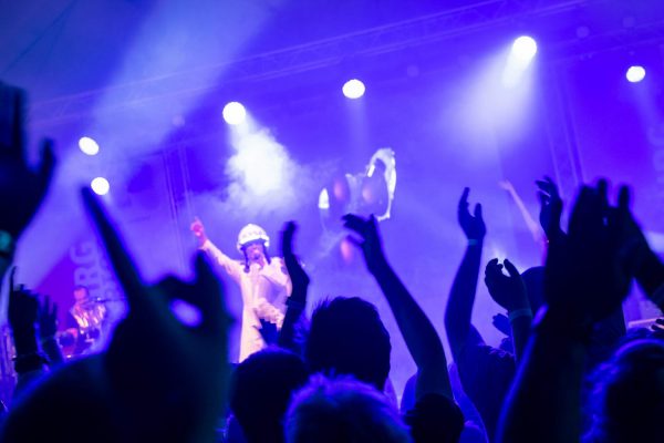 Titelbild Startseite von TOP10-Partybands. Blick auf die Bühne durch Publikum. Bühne im blauem Licht.