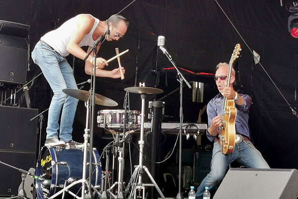 Schlagzeuger und Gitarrist nebeneinander auf der großen Bühne der Kieler Woche