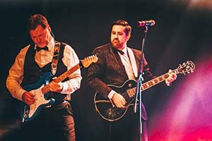 Zwei Gitarristen nebeneinander im Scheinwerferlicht